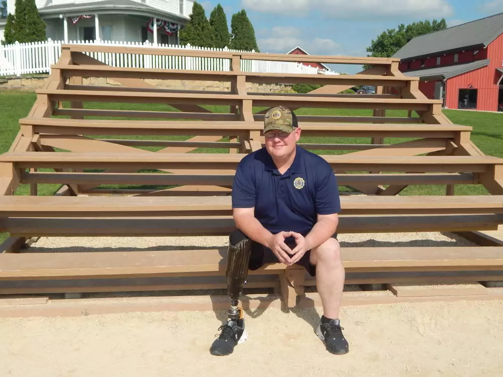 brian veteran sitting on bleachers by farmhouse